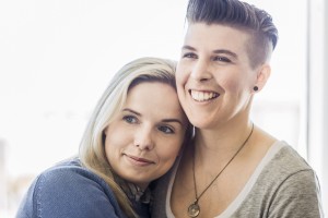 Smiling homosexual couple embracing at home